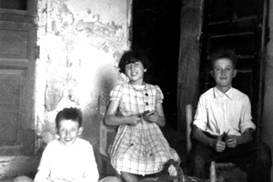 Grupo de niÃ±os sentados en la puerta de casa. Nombrevilla.