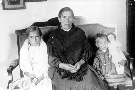 Abuela y nietas sentadas en casa. Blancas.