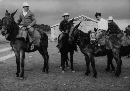Varios hombres montados en burro delante de una casa. Calamocha.