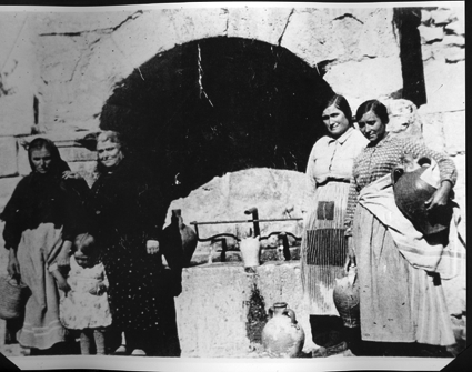 Mujeres con cÃ¡ntaros de barro recogiendo agua de la antigua fuente. Cosa