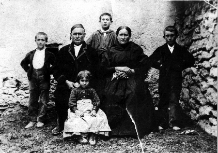 Retrato familiar de abuelos con nietos junto a una tapia. Fuente Claras.