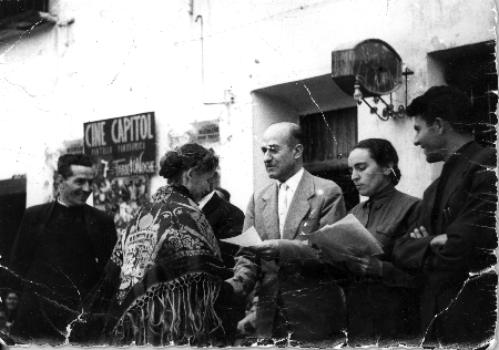 Gente leyendo delante de un cartel del cine Capitol. Fuentes Claras. AÃ±o 1959.