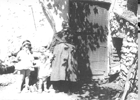 Abuela junto a sus dos nietas en la puerta de casa. Loscos.