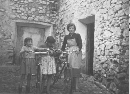 Madre e hijas con bicicletas en la puerta de casa. Loscos.