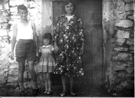 Madre con hijos en la puerta de casa. Loscos.
