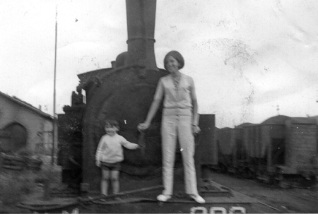 Mujer y niÃ±o delante de una locomotora. Ojos Negros.