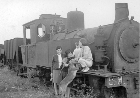 Grupo de jÃ³venes con perro junto a una locomotora. Ojos Negros.