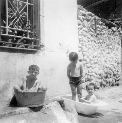 NiÃ±os baÃ±Ã¡ndose en barreÃ±os en una calle de Cuencabuena.