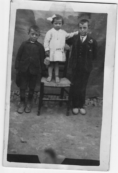 Retrato de dos niÃ±os y una niÃ±a sobre una silla. Torralba de los Sisones.